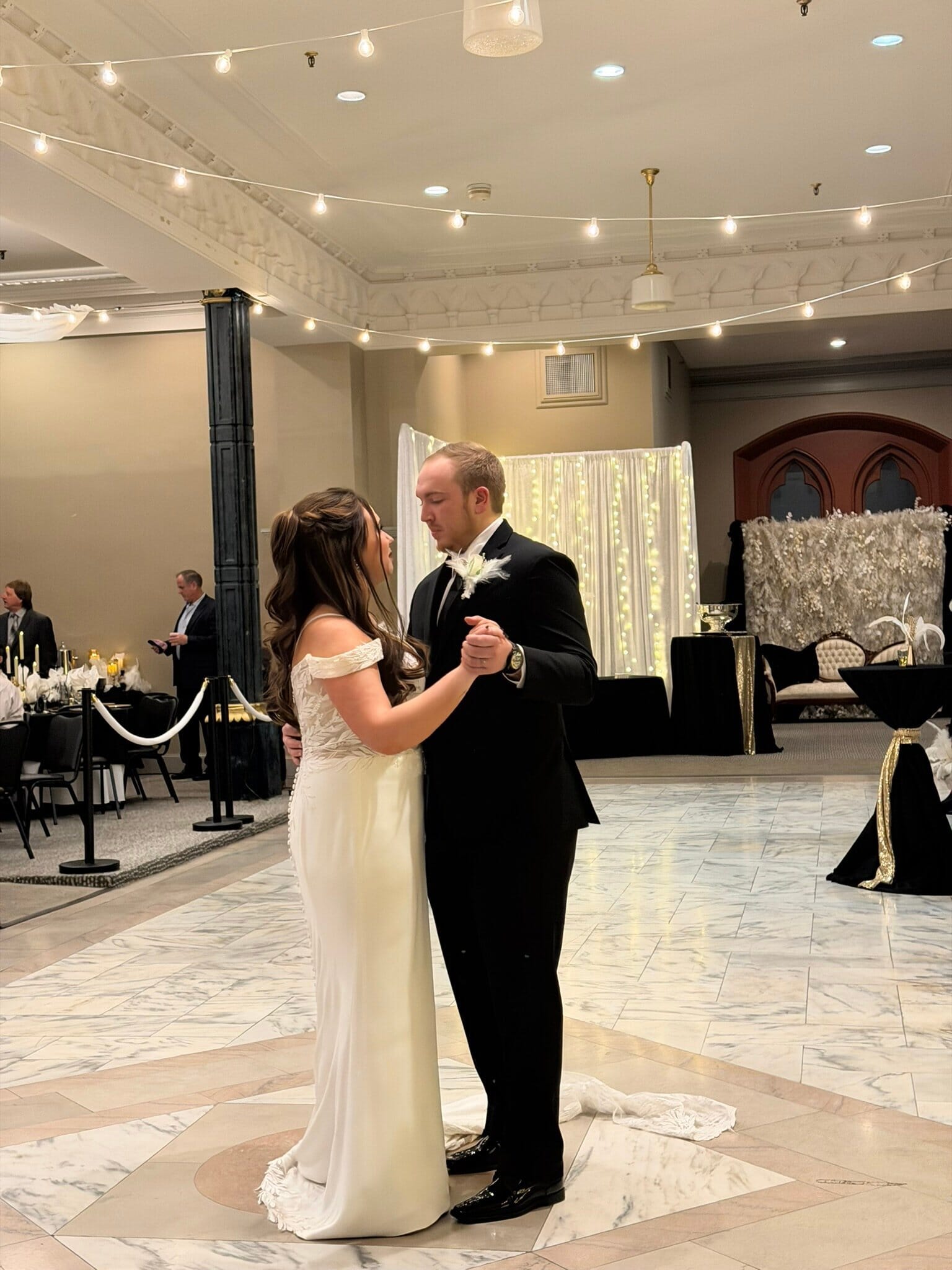 Bride and groom sharing their first dance under string lights at City View at Sterling Square in Evansville.