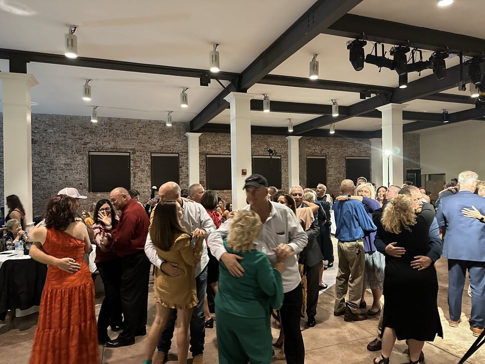 Packed wedding dance floor at City View at Sterling Square in Evansville, with exposed brick, black beams and columns and a ceiling lighting rig