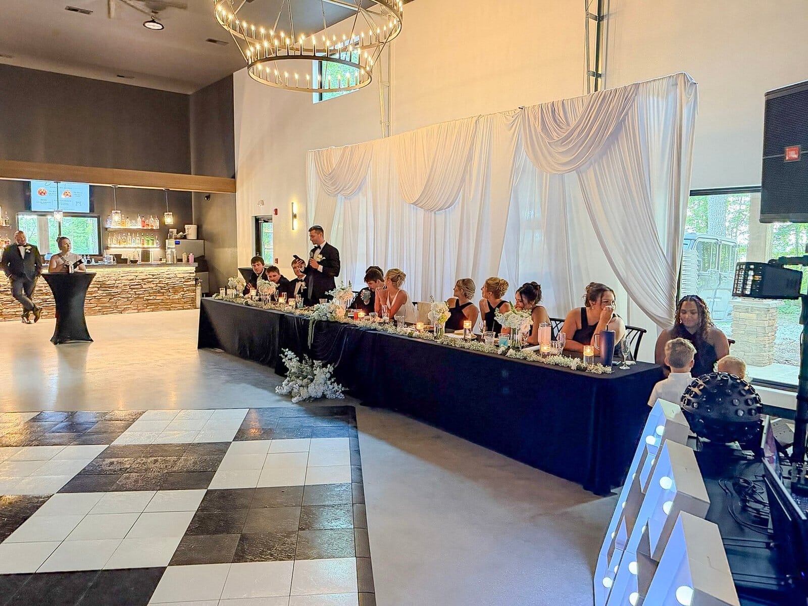 Head table and draped backdrop beside the checkered dance floor at a Highbanks Wedding & Events reception