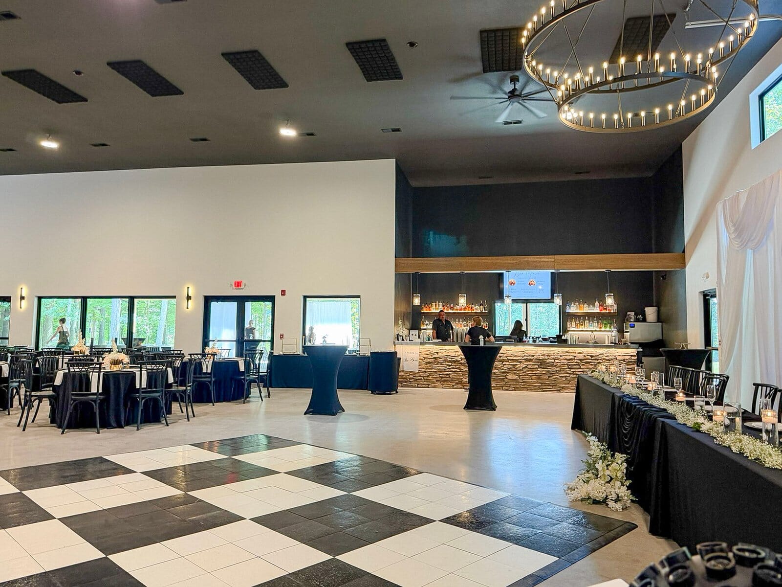 Highbanks Wedding & Events reception room with checkered dance floor, black-linen tables, stone bar and chandelier