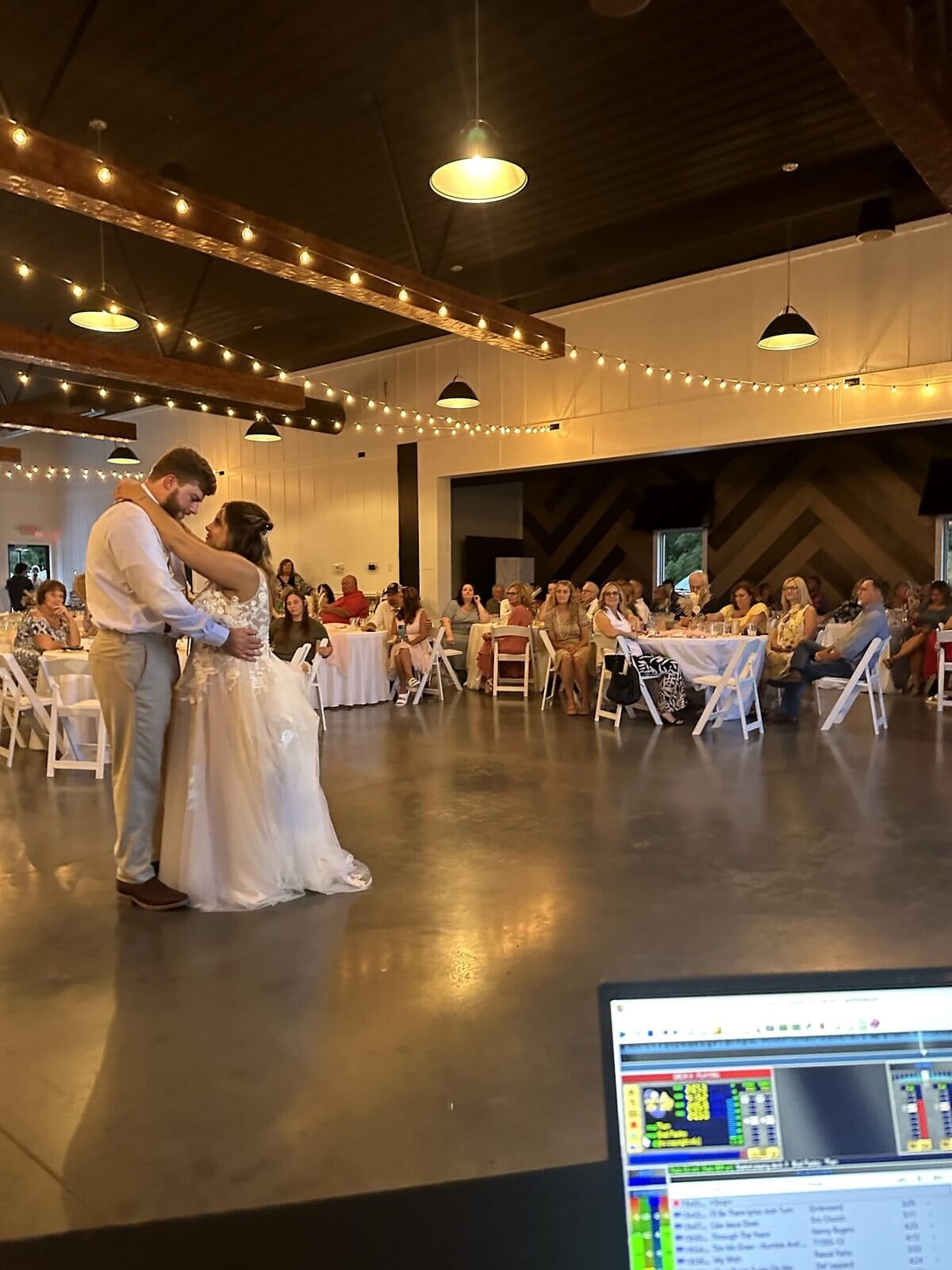 Bride and groom sharing their first dance in Event Barn A at Mahr Park Arboretum, seen from the DJ booth