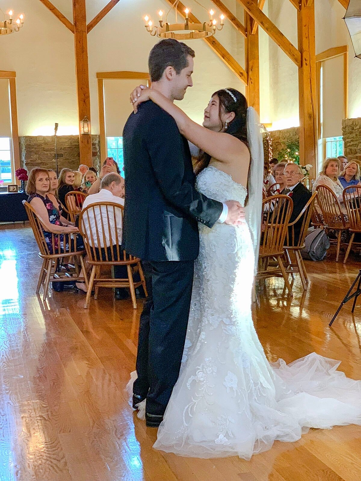 Bride and groom sharing their first dance on the wood floor of the Rapp-Owen Granary with guests watching