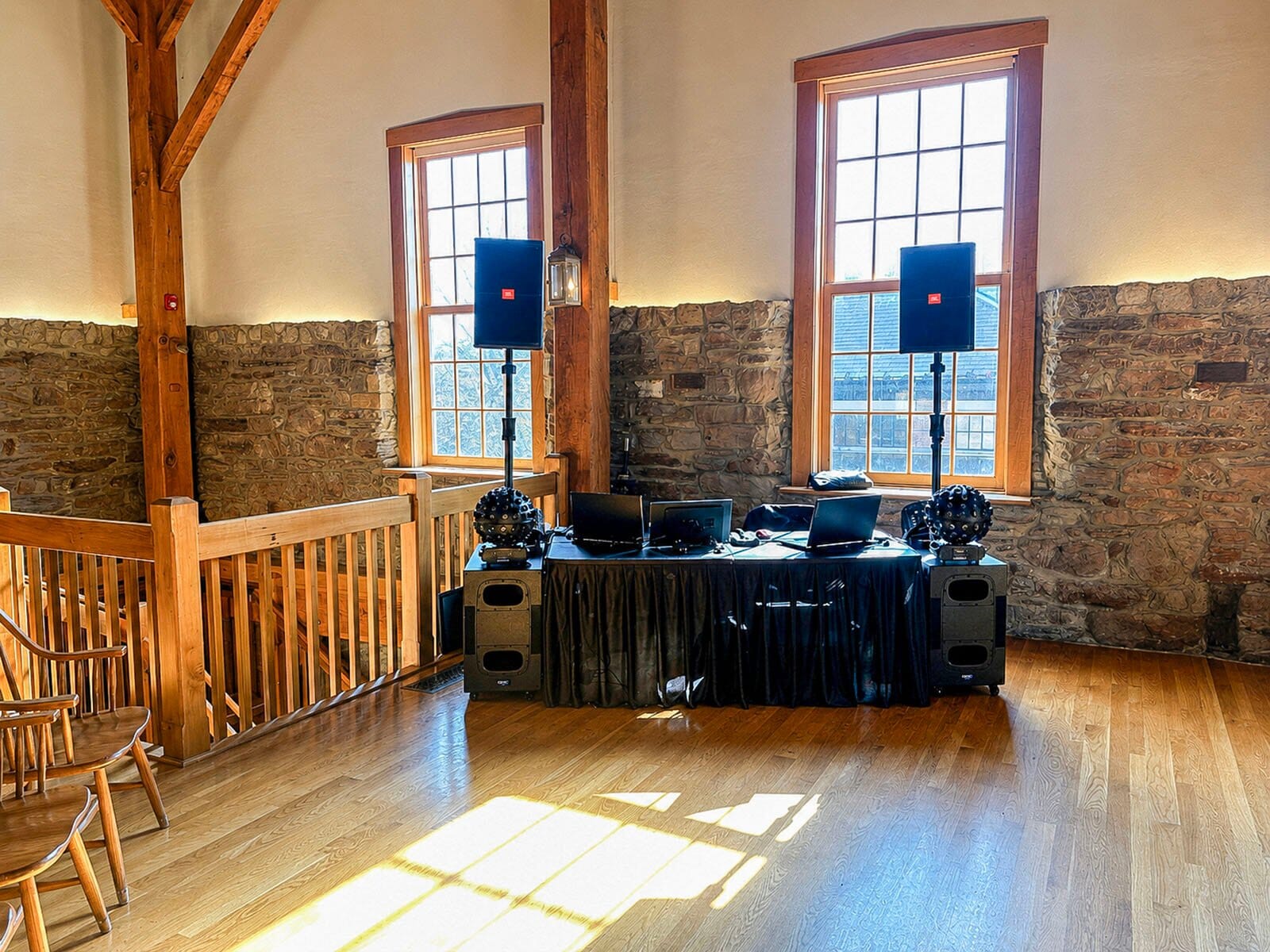 DJ booth set against the stone wall and tall windows inside the Rapp-Owen Granary before a wedding reception